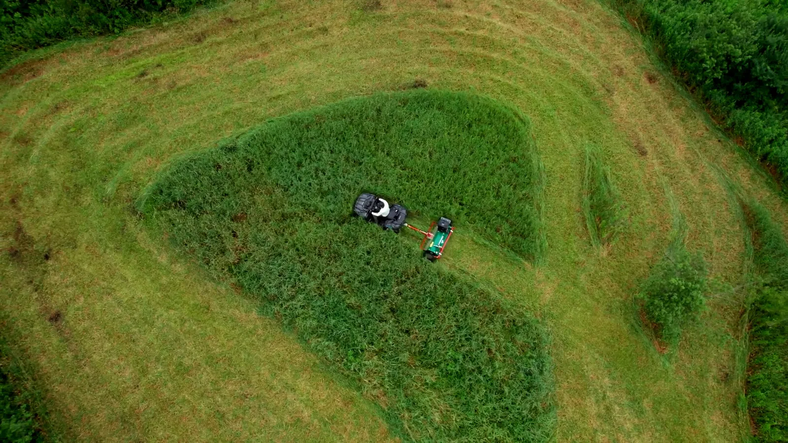 Vista aerea de un cuatriciclo con una desmalezadora de arrastre Wessex cortando pasto alto en un lote
